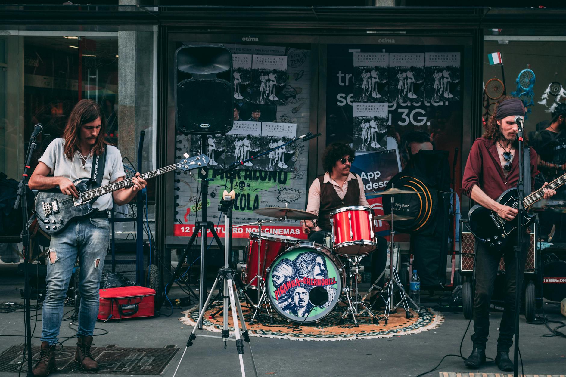 Indie band performing live on a street with guitarists and drummer entertaining the crowd.