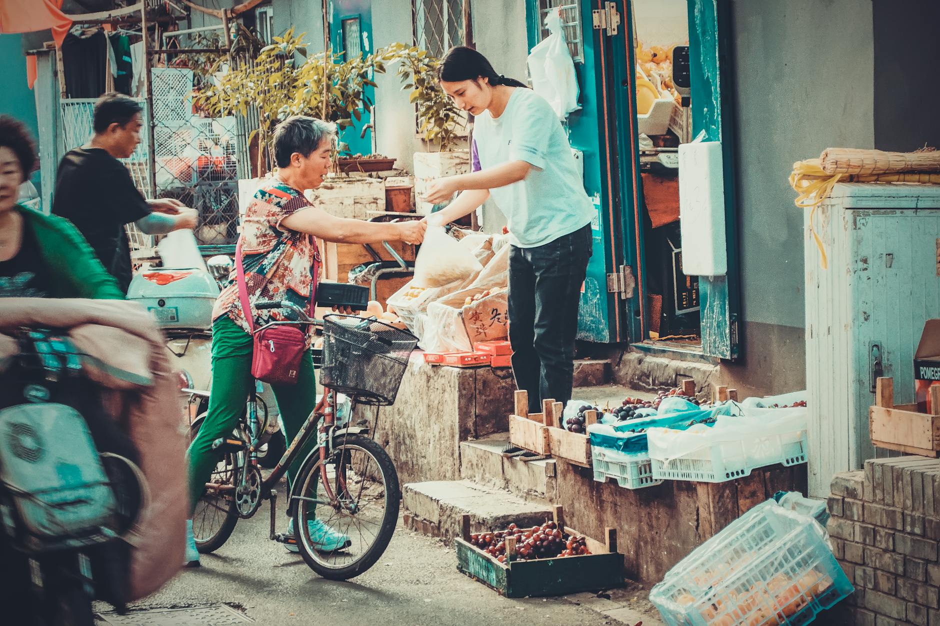 Local market scene in Beijing with a street vendor selling fruits to a cyclist.