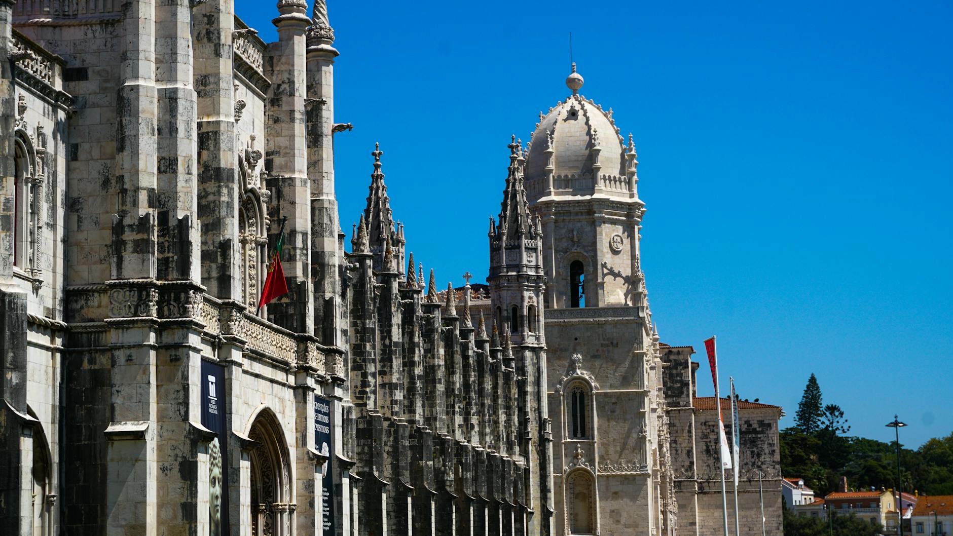 Majestic view of Jeronimos Monastery's intricate architecture under a clear blue sky in Lisbon, Portugal.