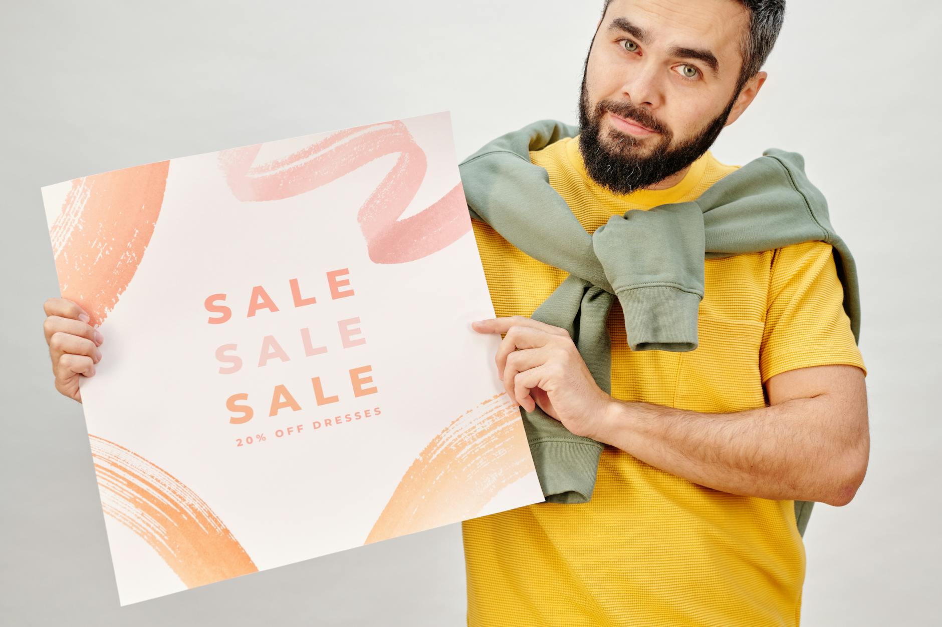 Man holding a sale poster advertising 20% off dresses. Perfect for Black Friday promotions.