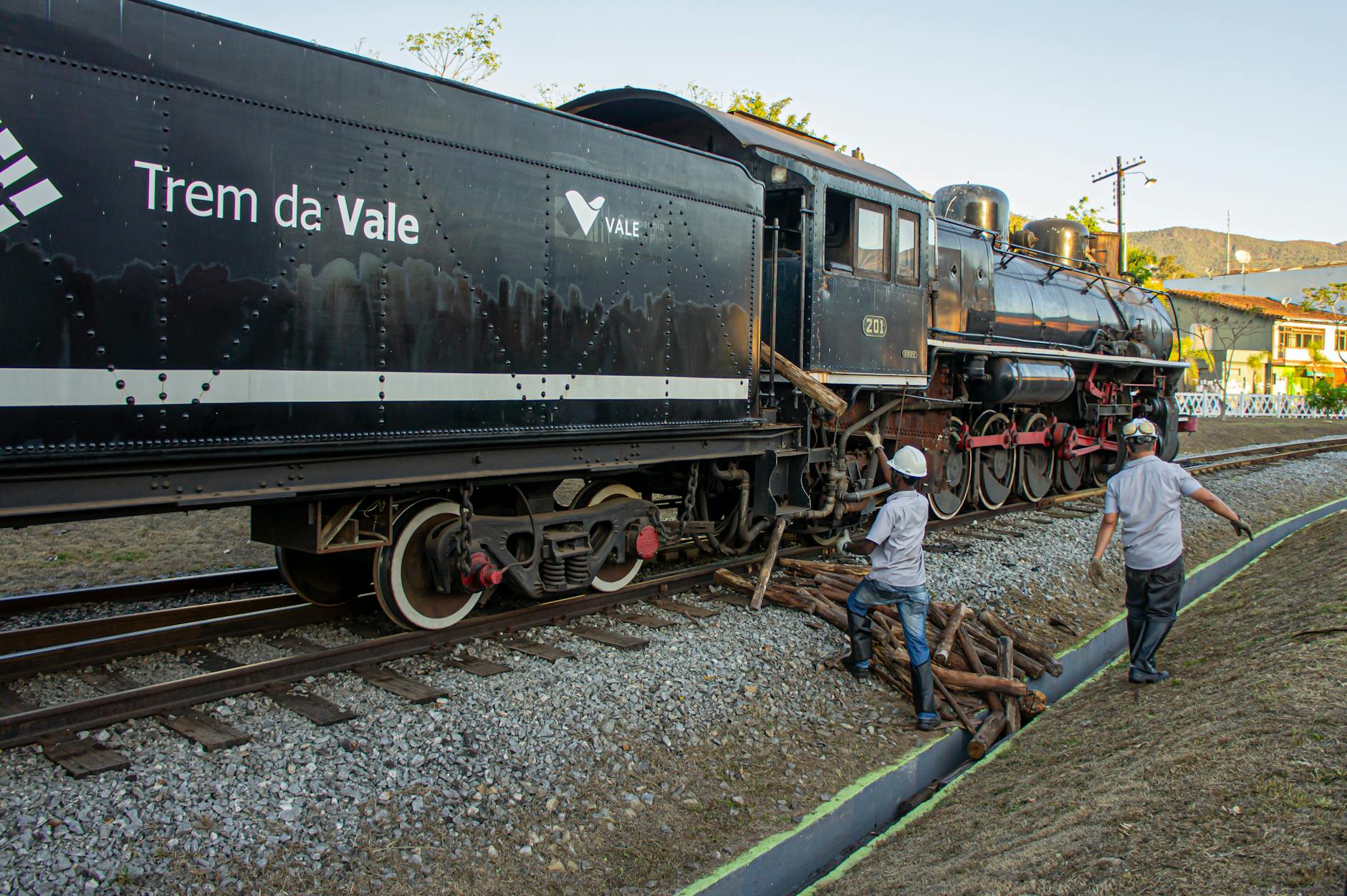 NOS Alive: onde vale a pena ficar (e onde não vale) se vives em Lisboa 5 Men working on a Trem da Vale locomotive with wooden supplies on the tracks.