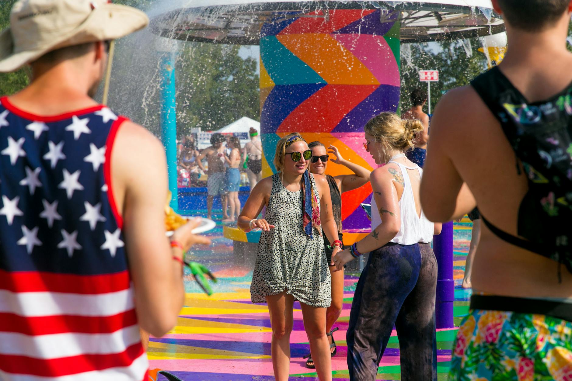 People enjoying a lively summer festival with colorful water fountain and playful atmosphere outdoors.