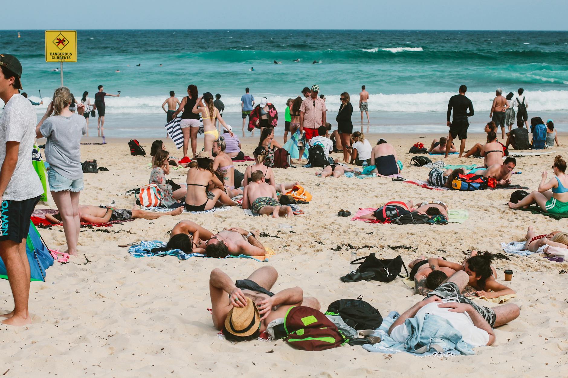 Praias Perto De Lisboa Quando Está Vento: Onde Ainda Dá Para Curtir 4 People enjoying a sunny day at Bondi Beach, Australia, with vibrant ocean waves and lively atmosphere.