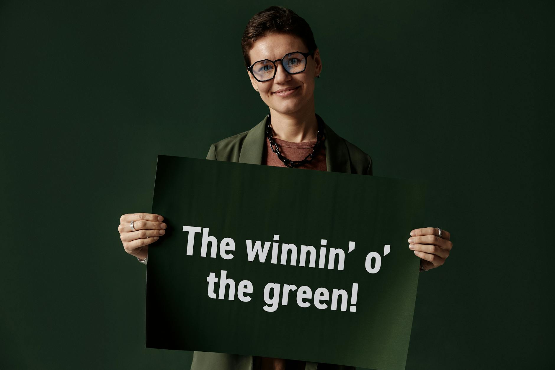 Person holding a St. Patrick's Day sign reading 'The winnin' o' the green.'