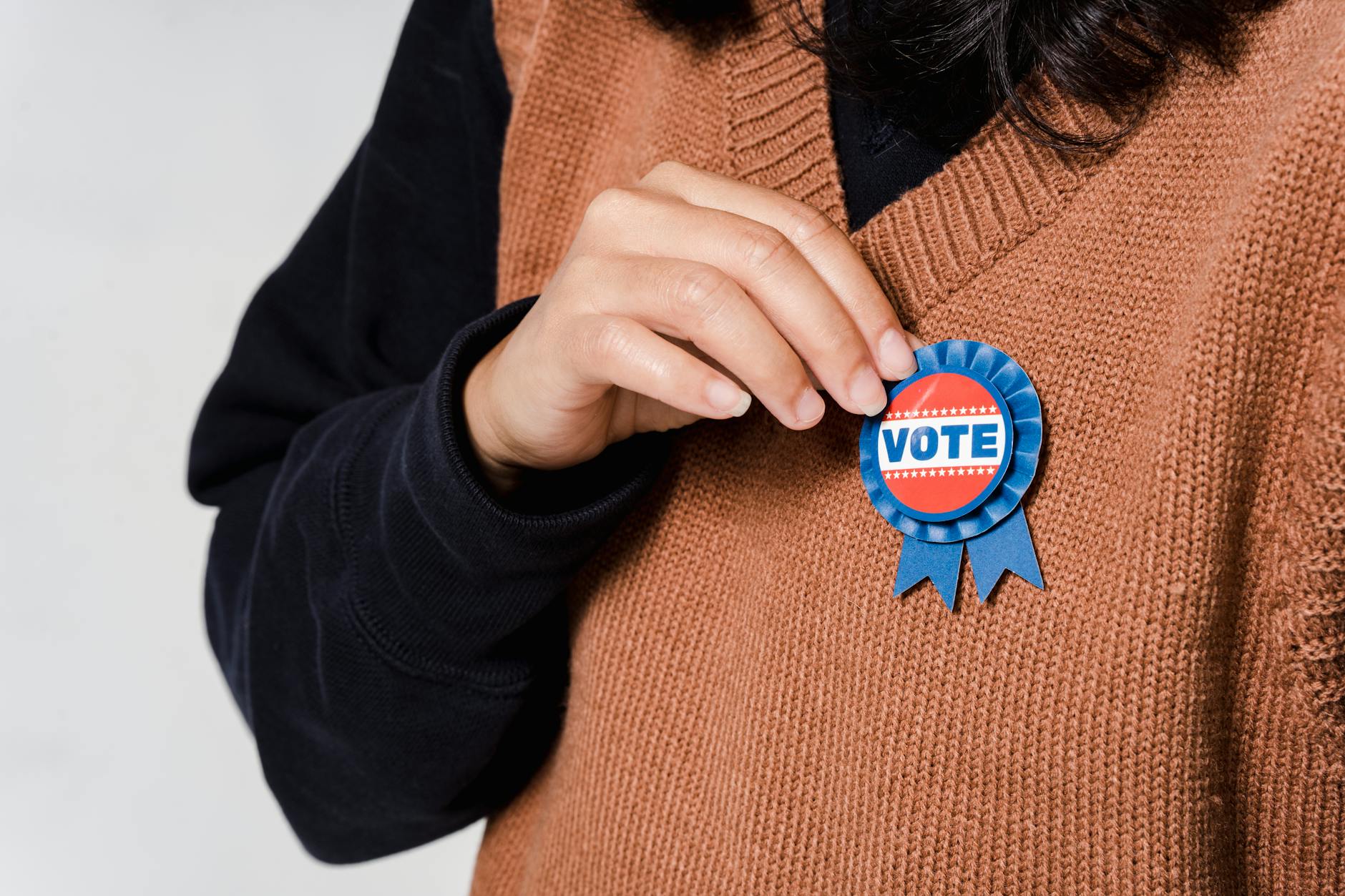 Person wearing a 'Vote' badge, symbolizing participation in democracy and elections.