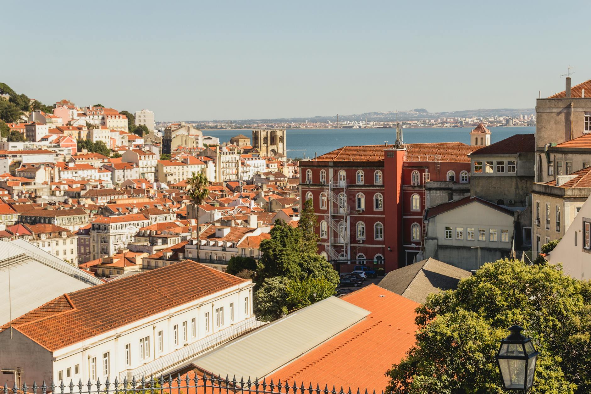 Scenic cityscape of Lisbon's Alfama district, featuring historic architecture and the Tejo River in the background.