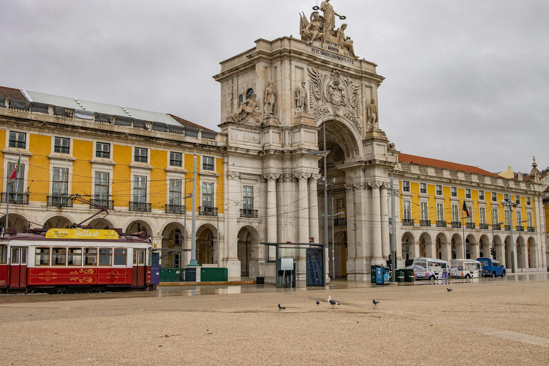 Scenic view of Lisbon's Arco da Rua Augusta with a tram passing by in a central city square.