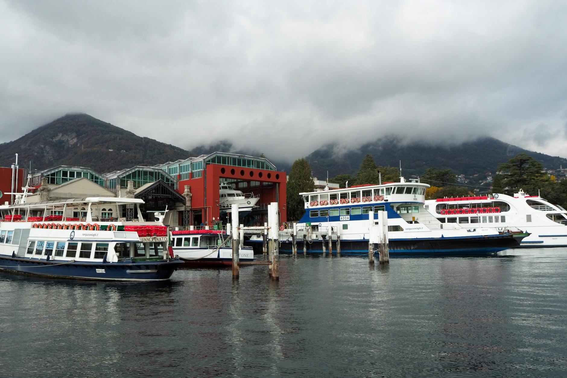 Alkantara: como aproveitar Lisboa em novembro com programas diferentes 8 Serene scene of ferries docked at Como's port with mountains and clouds in the backdrop.