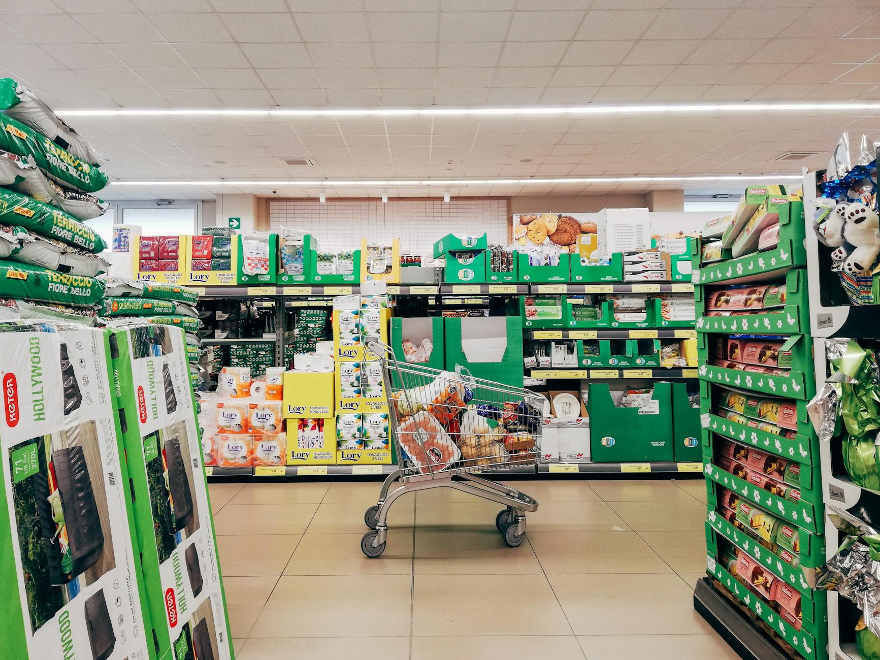 Shopping cart in a vibrant supermarket aisle in Padova, Italy.