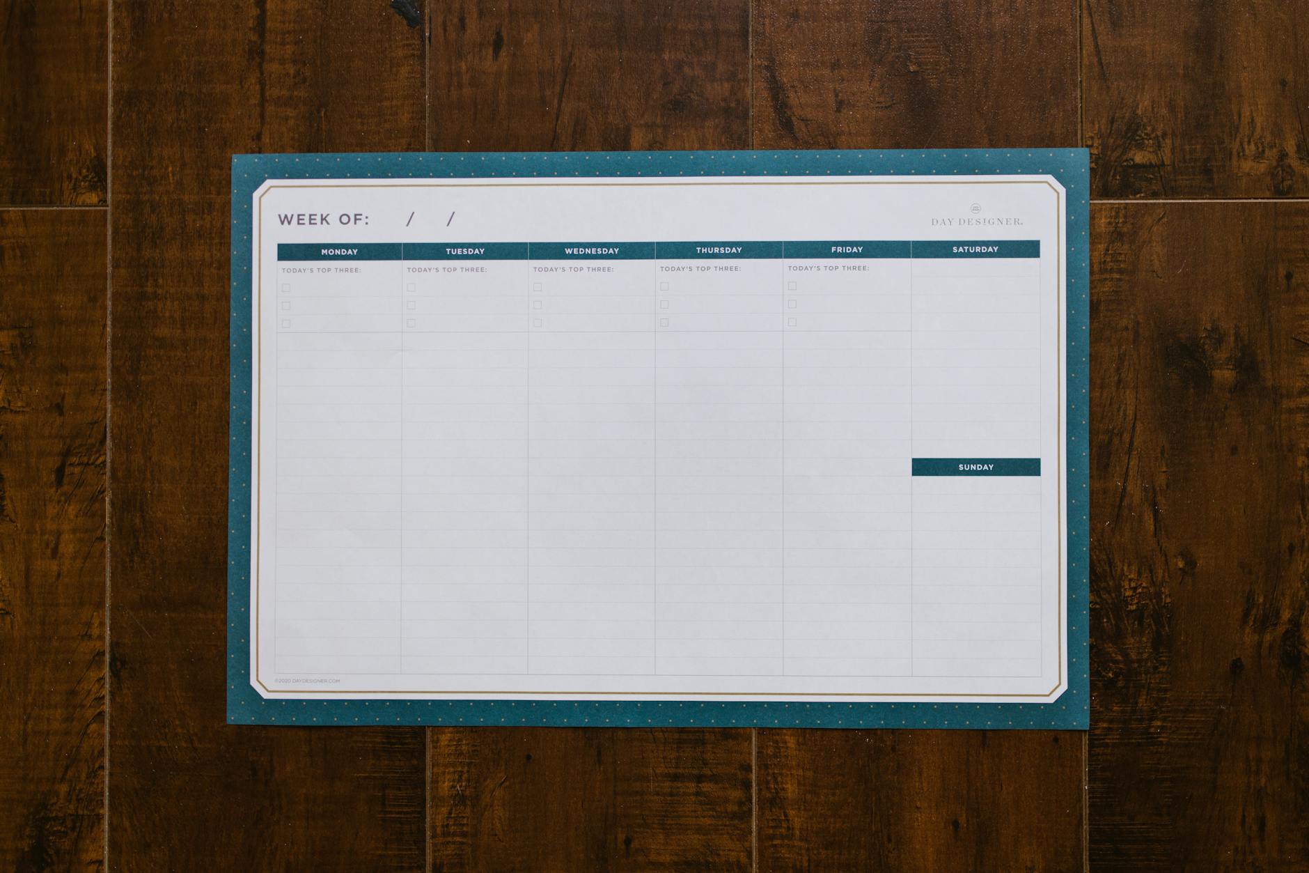 Top view of a blank weekly planner on a wooden surface, perfect for organizing your week.