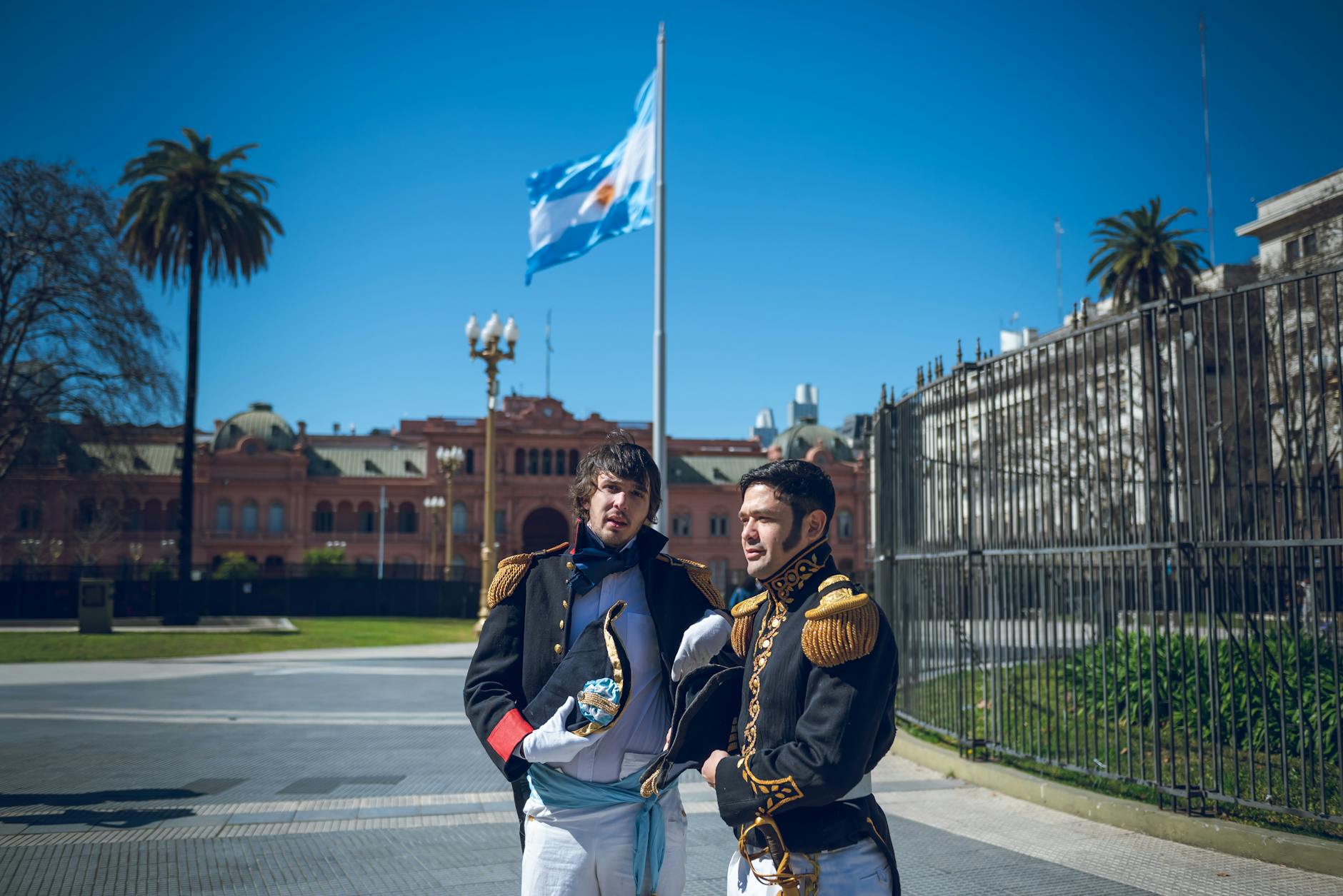 Two men in period costumes pose outside Casa Rosada in Plaza de Mayo, Buenos Aires.