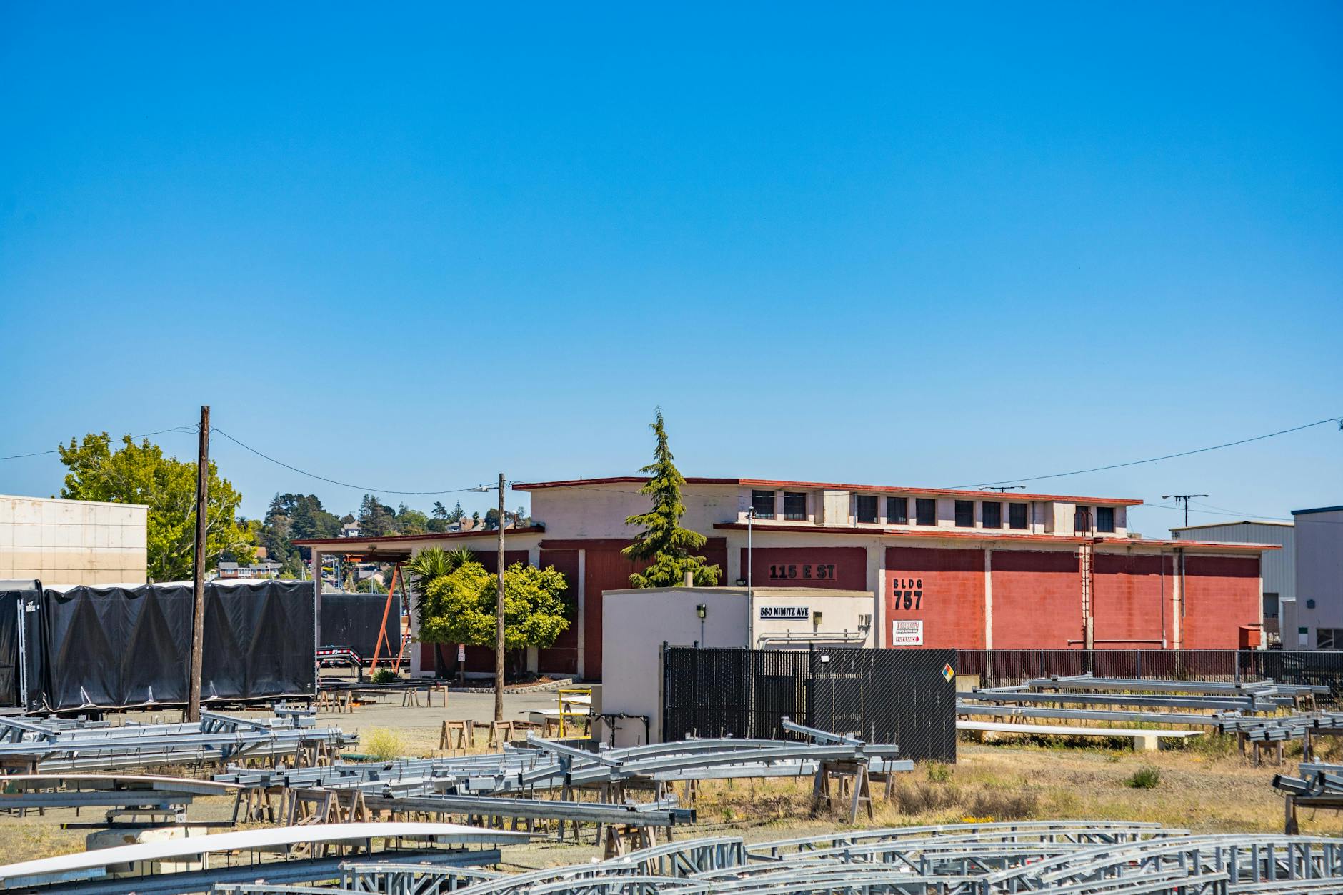 Warehouse building exterior with steel structures in an industrial setting under a clear blue sky.