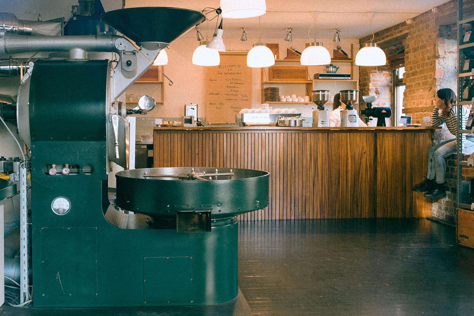 Warm and inviting café interior with coffee roasting machine and bar seating.