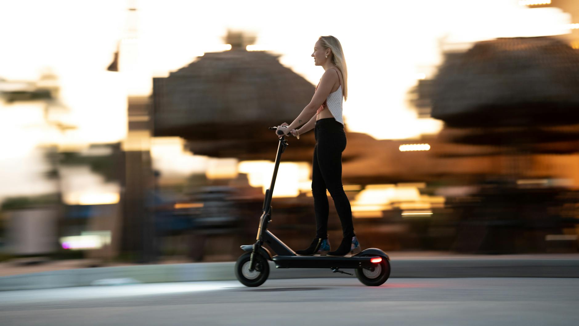 Woman enjoying an evening ride on an electric scooter with motion blur capturing speed and excitement.