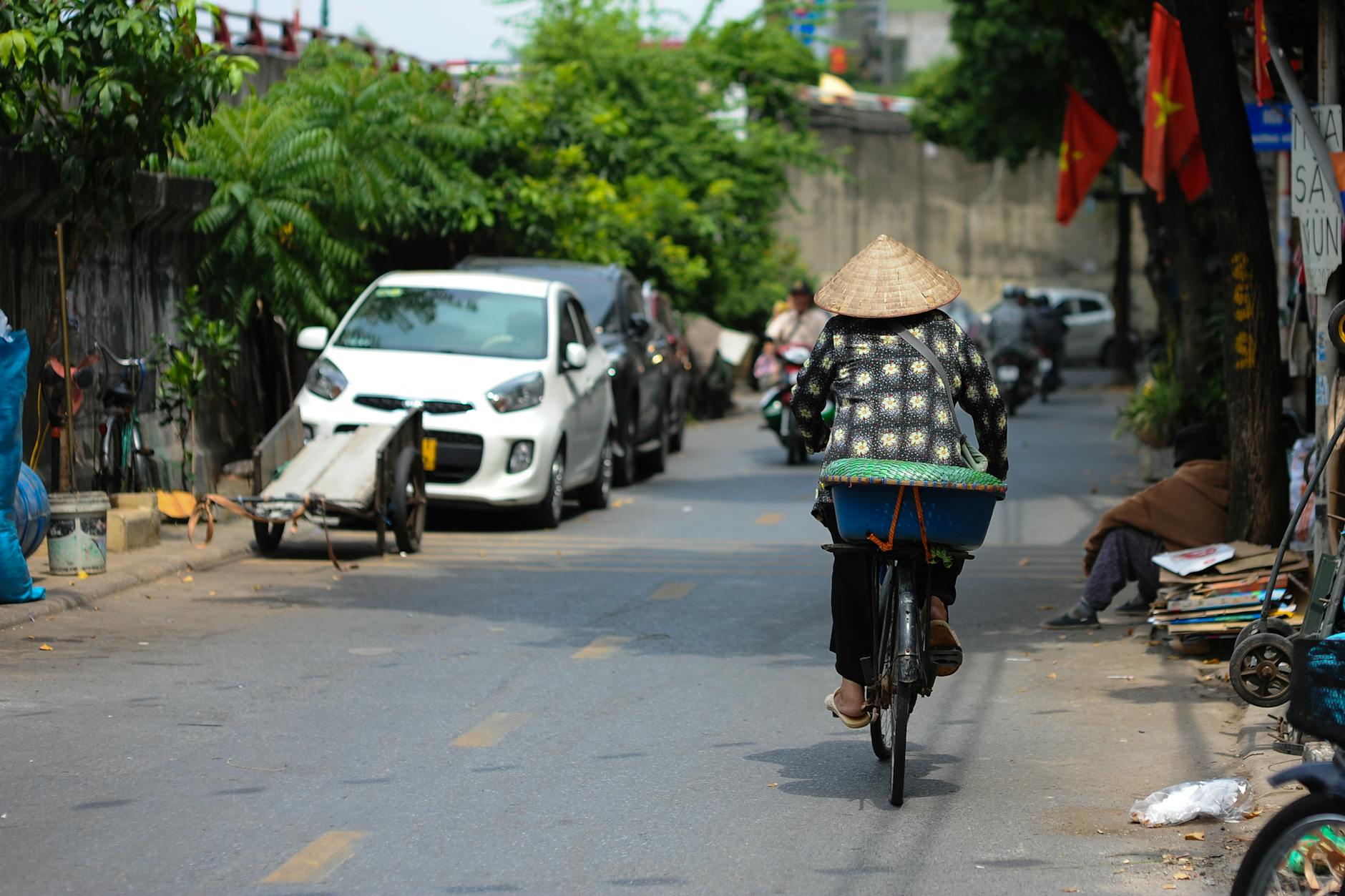 Os Melhores Jardins Em Lisboa Para Um “Reset” Mental 4 Woman on bicycle in Vietnamese street with conical hat, vibrant urban life.