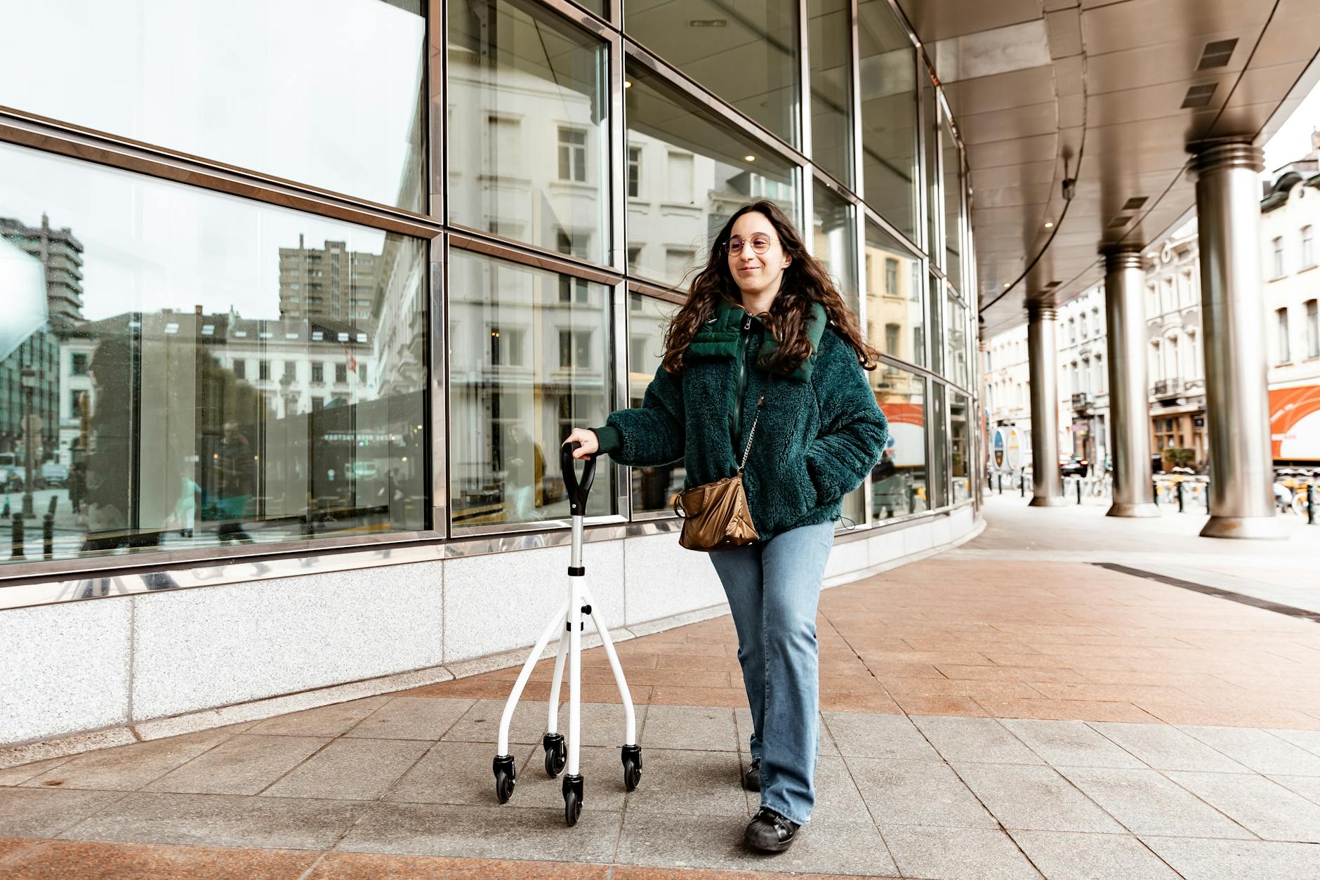 Young woman using a rollator while walking outside in a bustling city environment. Vibrant urban lifestyle captured outdoors.